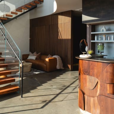 Red wood floating treads with frameless glass railing rise beside a wood-slat wall in a modern spa reception.