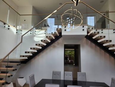 Mirrored mono stairs with white oak treads and standoff-mounted glass railings flank a central landing.