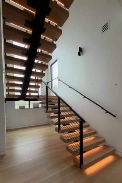 White oak floating stair with LED-lit treads on a black mono stringer with black rod railing