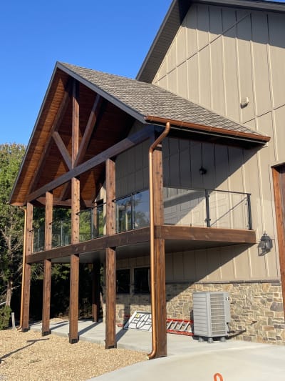 Timber-frame gable porch with a black-post glass balcony railing