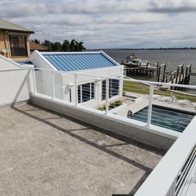 White powder-coated rod railing edges a rooftop above a pool and boat docks.