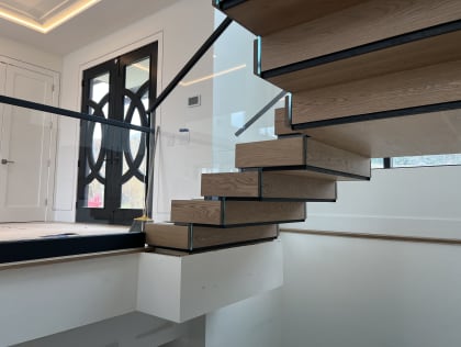 Oak Stack floating stair with a hidden built-in stringer beside frameless glass with a slim black top cap