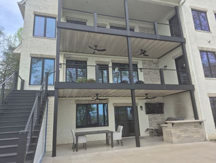 Dark cable railing on two stacked covered decks and a long exterior stair on a white brick home.