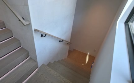 Oak stair treads with LED-lit nosings and a wall-mounted wood handrail in a stone-clad stairwell
