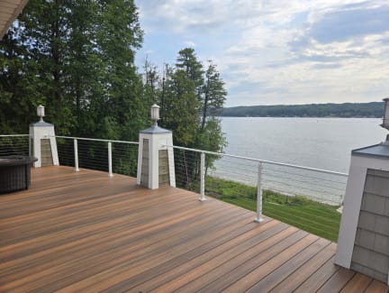 White posts and cable infill along a composite deck overlooking a lake.
