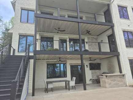 Black cable railing on stacked covered decks and an exterior stair of a white brick home.