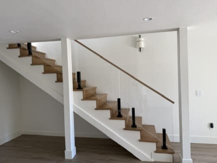 Black Ascend Talons hold glass panels with a white oak rail along an open white stringer stair.