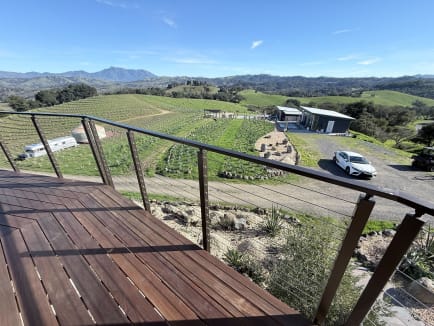 Bronze-toned cable railing edges a hardwood deck overlooking vineyards and rolling hills.