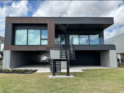 Contemporary dark-clad home with a black exterior stair and horizontal rod railing plus glass railing at the roof deck.