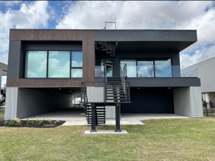 Contemporary dark-clad home with a black exterior stair and horizontal rod railing plus glass railing at the roof deck.