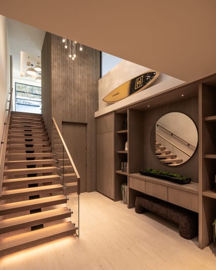 Light oak FLIGHT floating stair with LED-lit treads and frameless glass in a base rail rising through a wood-paneled entry.