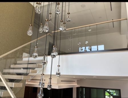 Frameless glass loft and stair railing with a wood cap behind cascading glass pendants