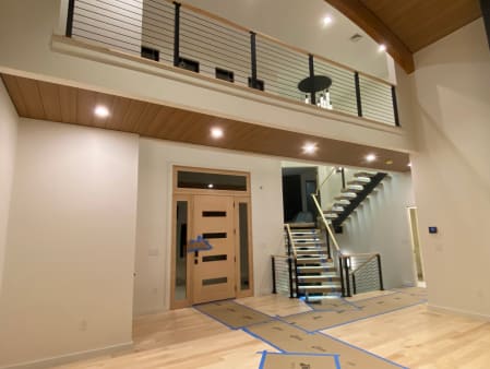 Two-story entry with a floating LED stair and black cable railing on the loft above