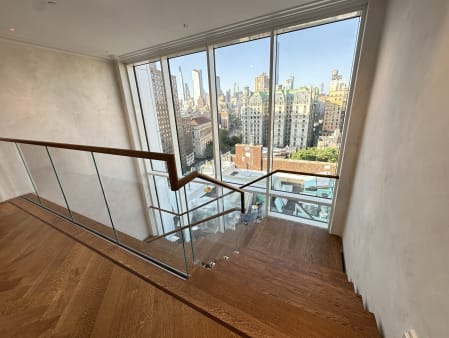 Recessed base rail glass with a wood handrail at a stair opening overlooking the Manhattan skyline