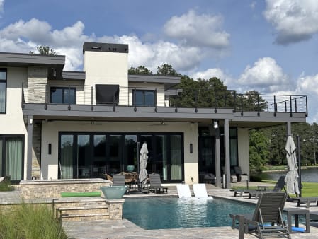 Black Onyx rod railing wraps the roof deck of a modern lake house above a pool terrace