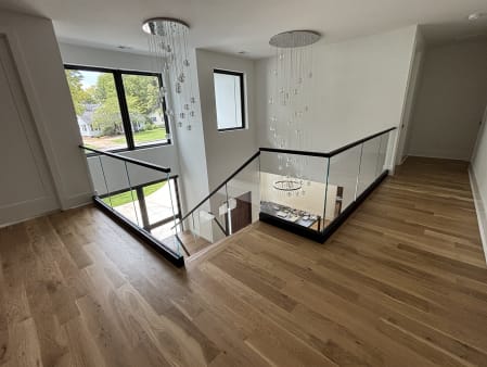 Black base rail glass with a black cap wraps a stair opening under crystal pendant chandeliers