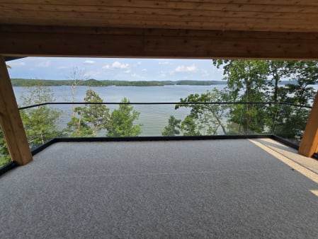 Frameless base rail glass under timber beams frames a sweeping lake and island view
