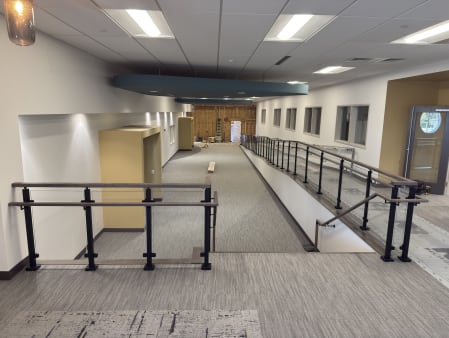 Post glass guardrail and ADA handrails along a ramp in a commercial building