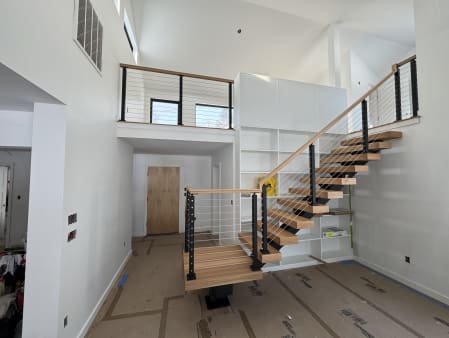 Red oak FLIGHT Mono stair turning at a post-supported landing with black cable railing and oak handrail