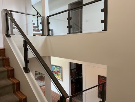 Bronze posts with glass panels follow a carpeted stair to a glass-railed landing.
