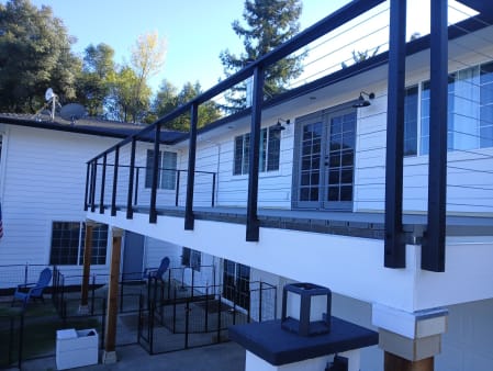 Black side-mount cable posts fastened to the fascia of an upper deck on a white home.