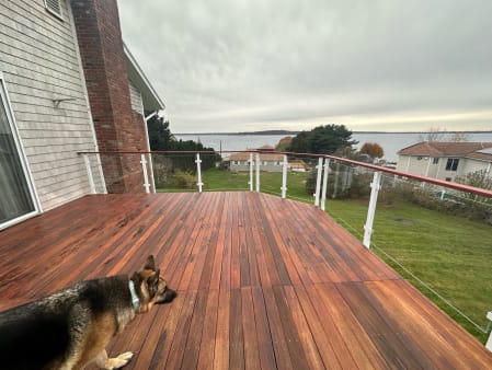 Bright white posts with glass panels and an Ipe cap rail around an Ipe deck overlooking a bay.