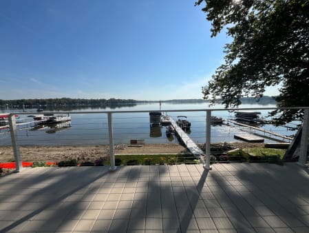 White posts with cable infill along a composite deck facing a lake with docks and boats.