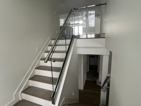 Frameless glass in a stainless base rail with a round stainless handrail along a split-level stair