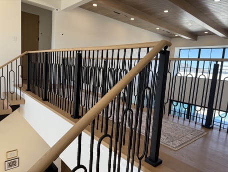 Oak handrail over black ornamental balusters at a loft corner