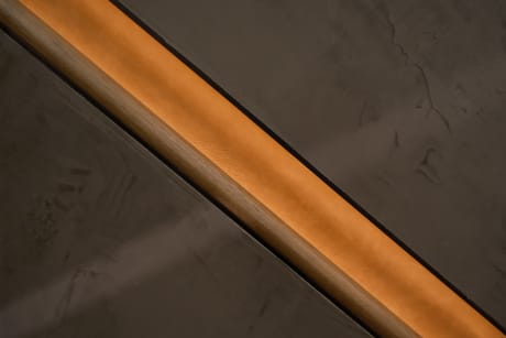 Close view of a wood handrail recessed in a softly lit wall channel.