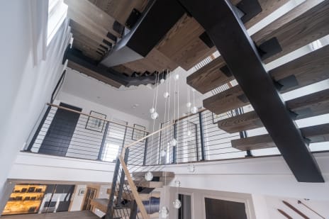Looking up at a black FLIGHT Mono stringer turning with oak treads, glass and cable railings above.