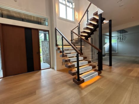 Walnut floating treads with Viewrail tread covers and under-tread LEDs on a mono stringer with glass and post railing in an entry.