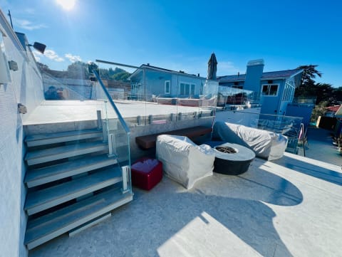 Frameless glass with Ascend Talon clamps lines a stone-clad stair leading to a sunny rooftop terrace.