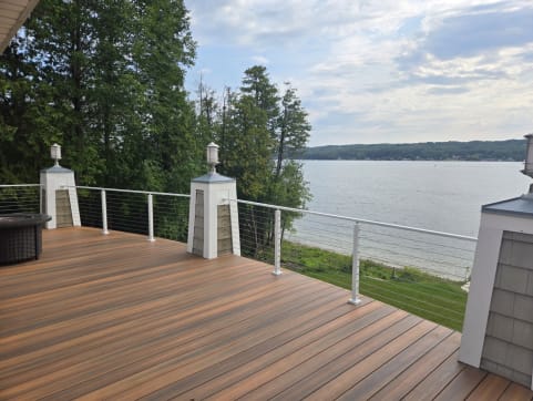 White posts and cable infill along a composite deck overlooking a lake.