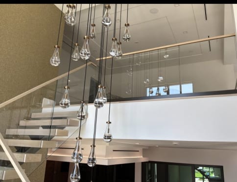 Frameless glass loft and stair railing with a wood cap behind cascading glass pendants