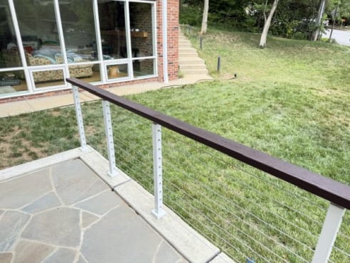 Cable railing corner with white posts and dark wood rail above a green lawn