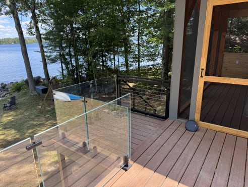 Laminated glass on surface talons meets black cable railing on a deck by the lake