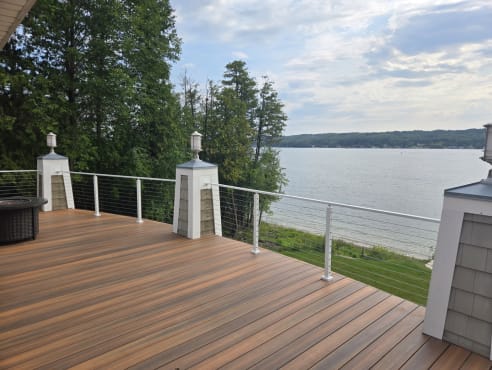 White posts and cable infill along a composite deck overlooking a lake.