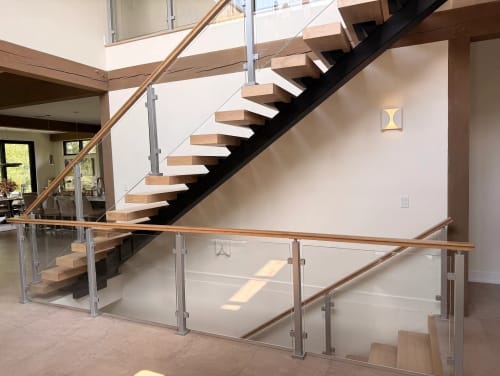 Black mono stringer floating stair with silver posts, glass panels and wood handrail