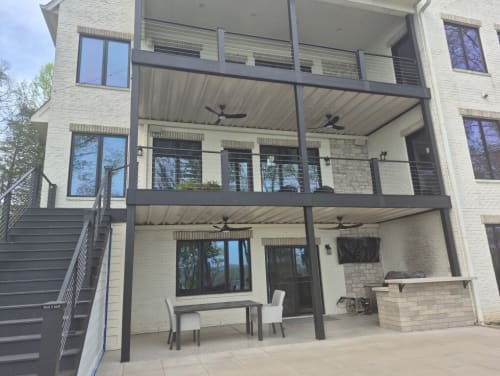Dark cable railing on two stacked covered decks and a long exterior stair on a white brick home.