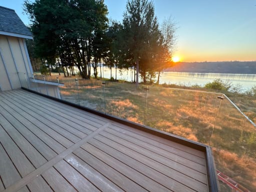 Glass railing deck facing a lake at sunset