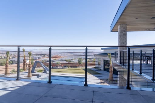 Black posts with Onyx rod infill and a hardwood cap rail line a terrace above a pool with desert views.