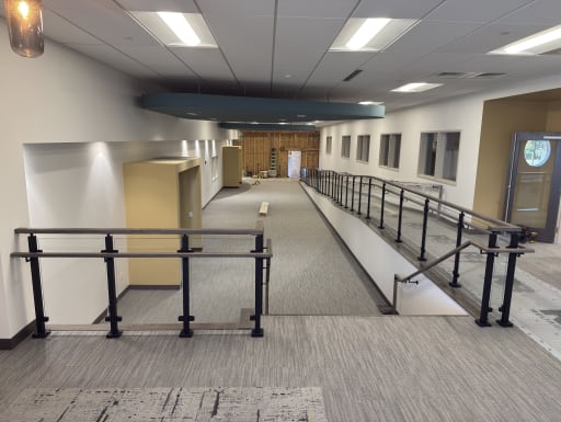 Post glass guardrail and ADA handrails along a ramp in a commercial building
