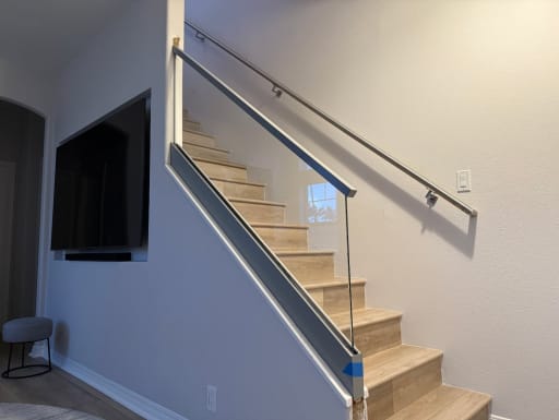 Silver base rail glass with an aluminum cap and a stainless wall handrail on a pale-oak stair