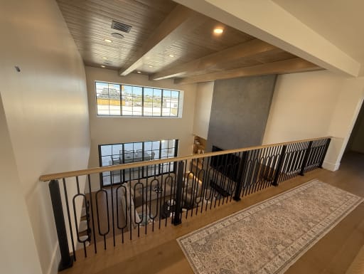 Black decorative balusters with an oak handrail along a loft overlooking a great room