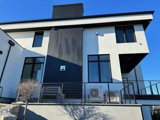 Cable railing runs along a terrace and exterior stair of a white modern home.