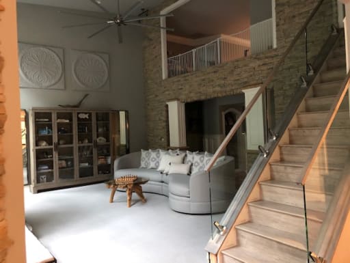 Frameless glass with wood handrail on surface talons follows a light stair beside a stone wall in a living room.