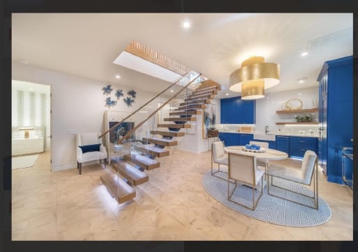 Floating wood treads with under-tread LED lighting and Vedera glass railing rise beside a bright kitchen and dining area.