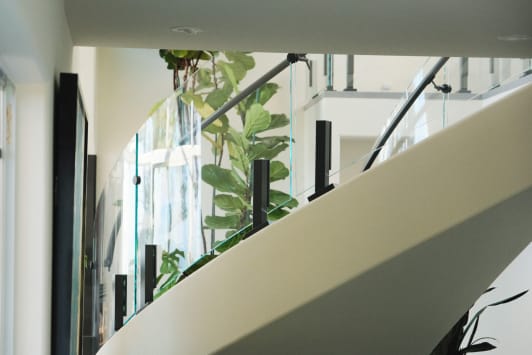 Curved glass panels on black talons with a black handrail sweep along a white curved stair stringer.