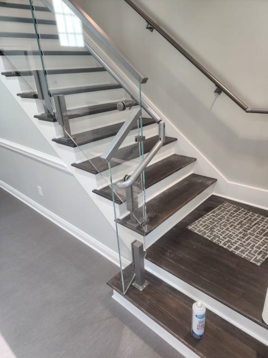 Stainless post glass railing and a curved stainless wall handrail at a commercial stair landing
